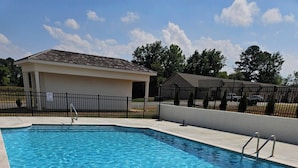 A rectangular swimming pool with clear blue water, surrounded by a tiled deck and a metal fence. - Madison Cozy House for Comfort and Relaxation (Madison)