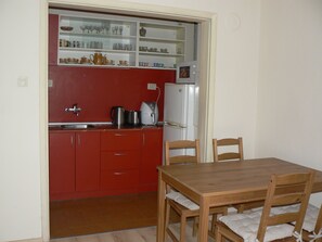Prepare meals and dine in this kitchen with a display shelf, refrigerator, and coffee maker.