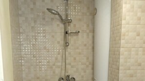 Un baño pequeño con azulejos, que incluye una ducha, un inodoro y un lavabo.