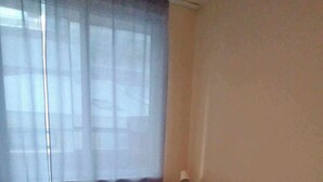 Una cama individual con colchón blanco y estructura de madera en una habitación con piso de madera.