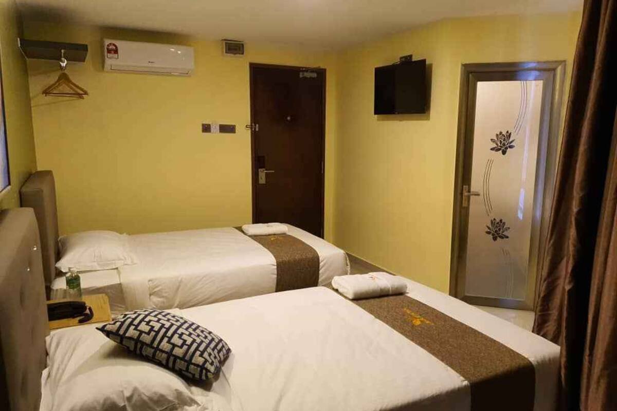 Une chambre d’hôtel avec deux lits, une télévision, un climatiseur et une porte ornée d’un motif décoratif.