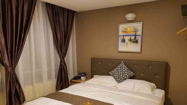 Een hotelkamer met een bed, een nachtkastje met een lamp en een schilderij aan de muur.
