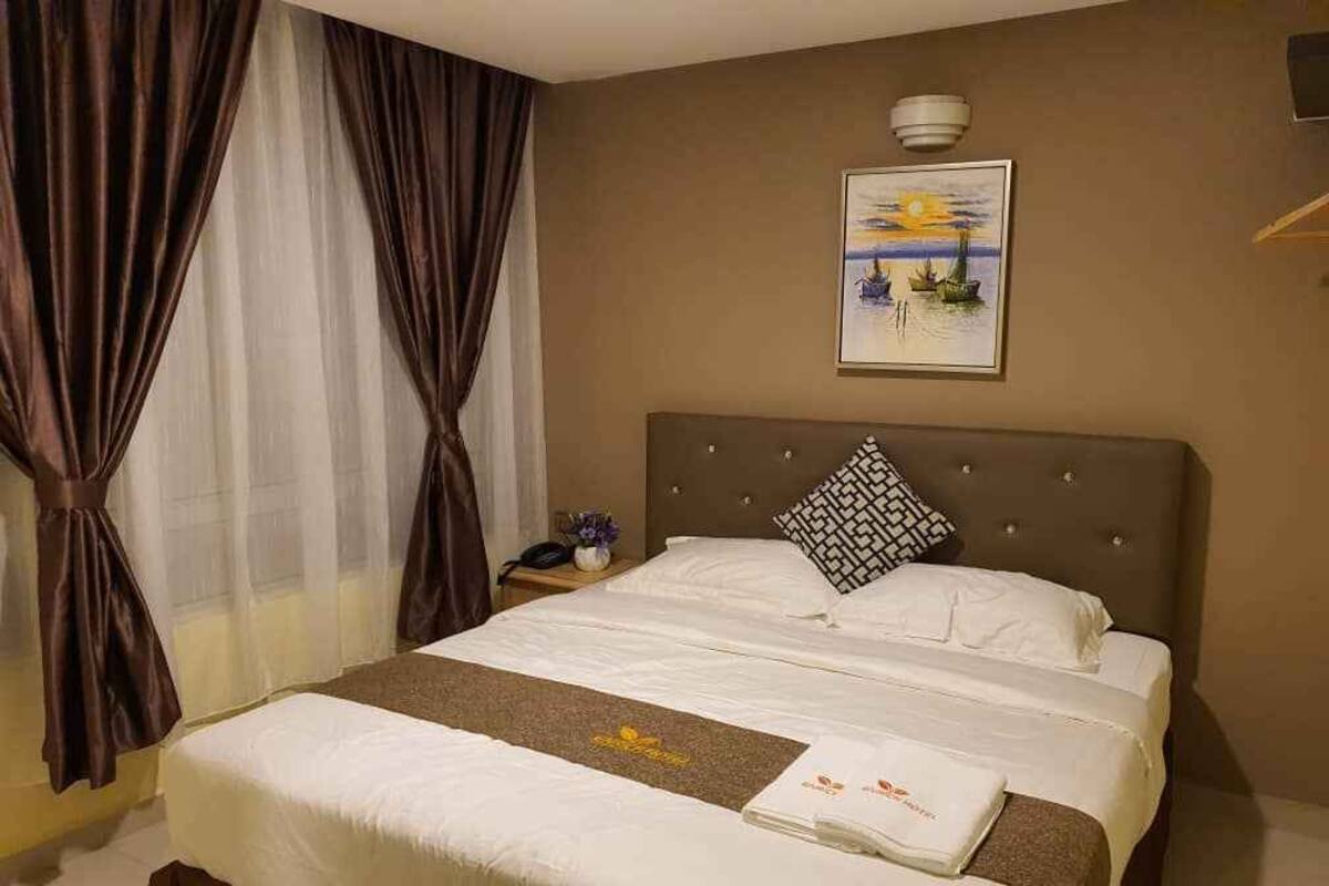 Une chambre d’hôtel avec un lit, une table de chevet avec une lampe et un tableau au mur.