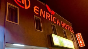 Het ENRICH HOTEL bord met een neon vogel logo.