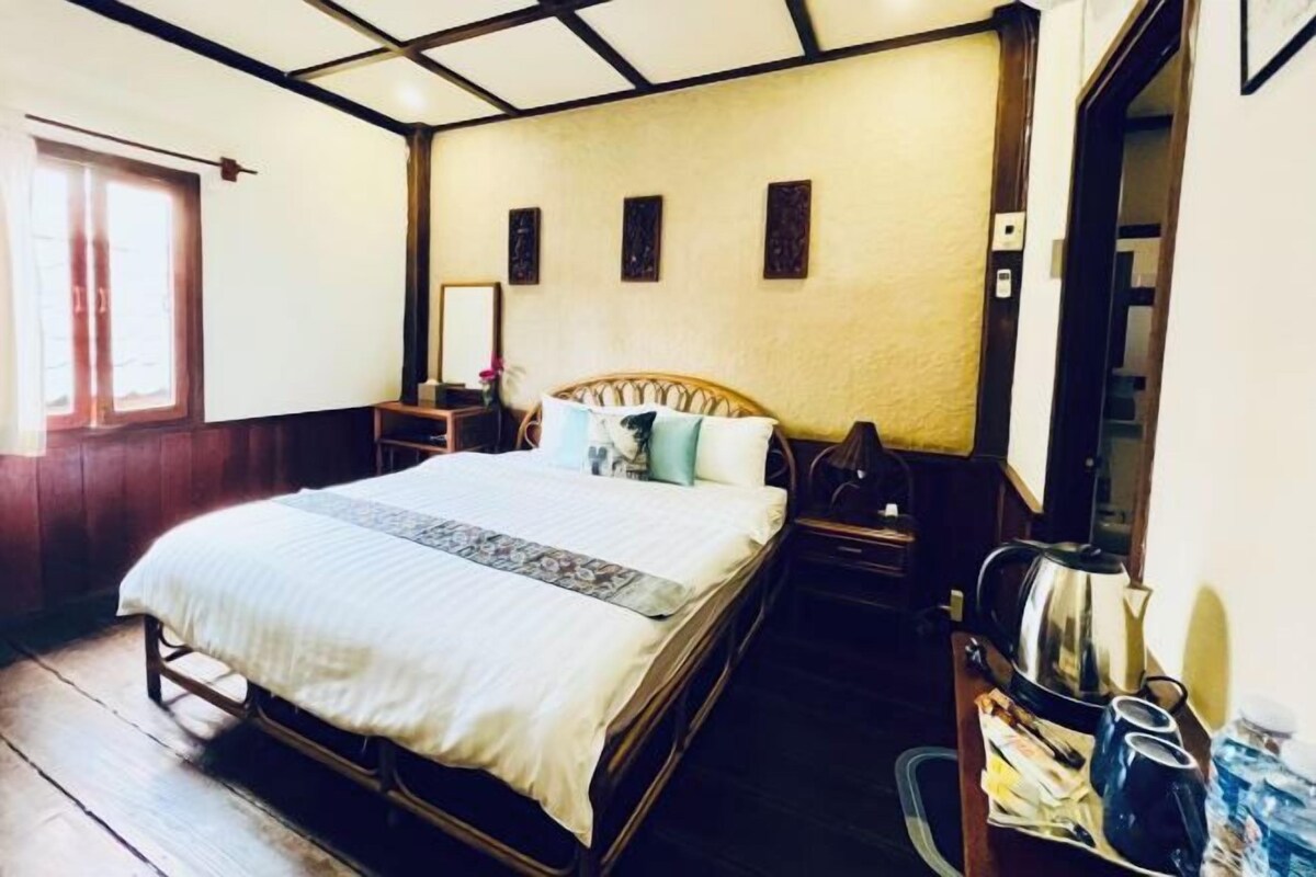 A bedroom with a wooden bed, a nightstand, a mirror, and a window.