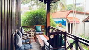 A wooden deck with seating, a mural, and a view of a building with a red roof. - Villa de Mekong (Vientiane)