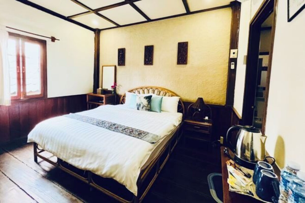 A bedroom with a wooden bed, a nightstand, a mirror, and a window.