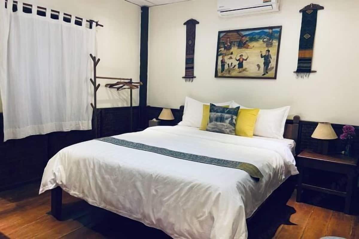 Quarto de hotel com uma cama grande, mesa de cabeceira, ar condicionado fixado na parede e um quadro.