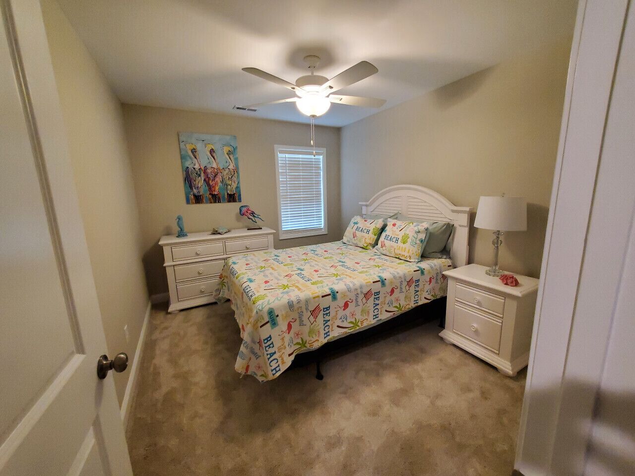 A bedroom with a bed, nightstands, a dresser, a ceiling fan, and a window with blinds.