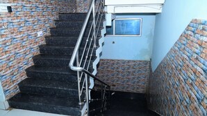 A staircase with black steps and a metal railing, surrounded by brick walls. - DhamStay Hotel Savashi Near Temple Puri (Puri)