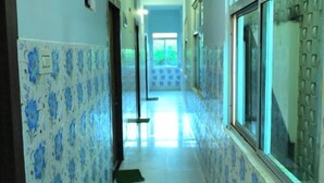 A hallway with patterned walls and a tiled floor, leading to a bright room with a window. - DhamStay Hotel Savashi Near Temple Puri (Puri)