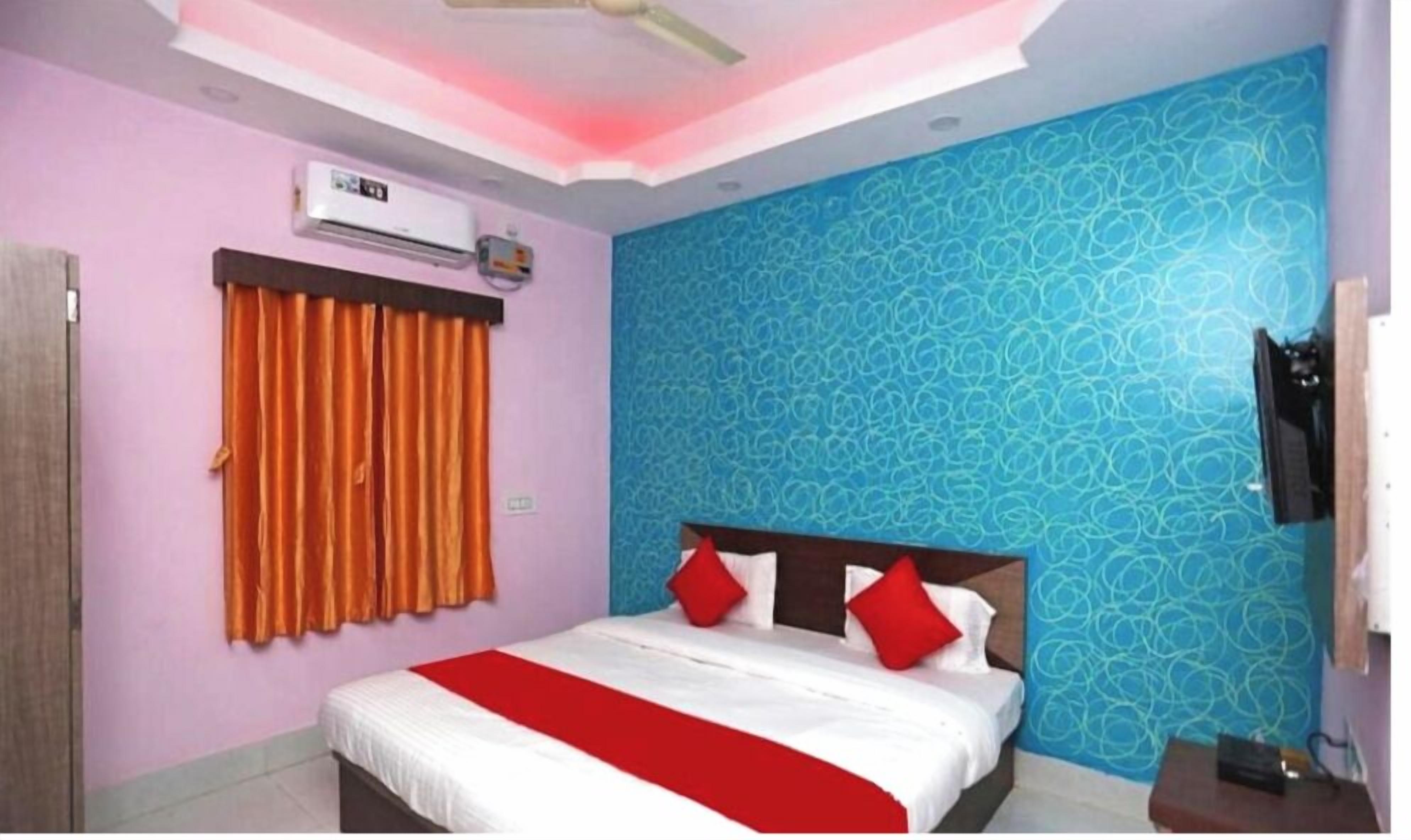 A bedroom with a bed, orange curtains, a ceiling fan, and a patterned wall.
