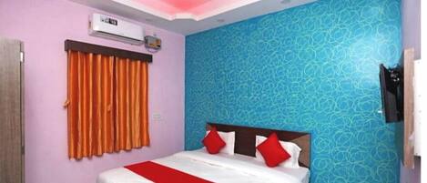 A bedroom with a bed, orange curtains, a ceiling fan, and a patterned wall.