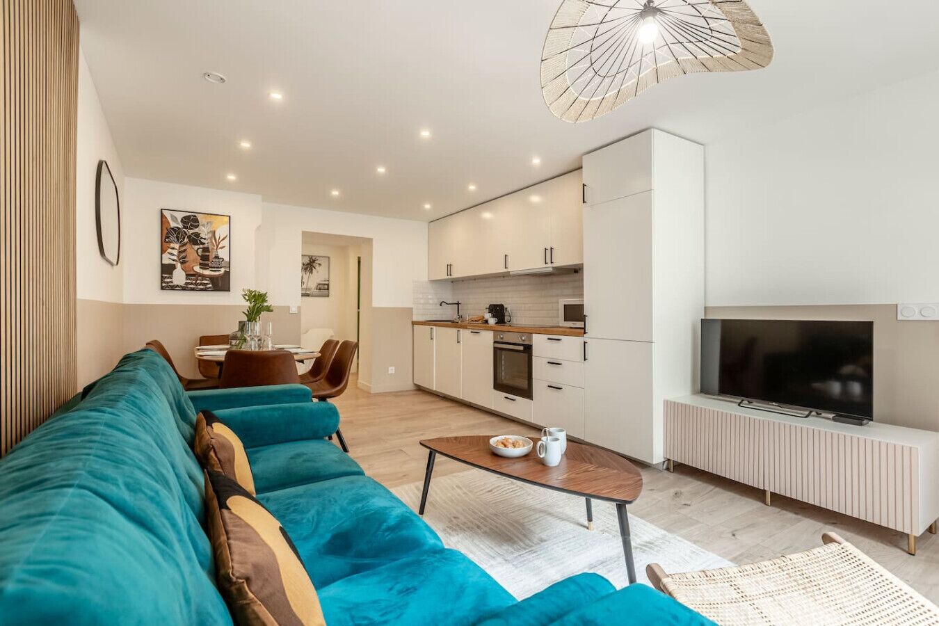 A modern living room with a teal sofa, a coffee table, and a TV.