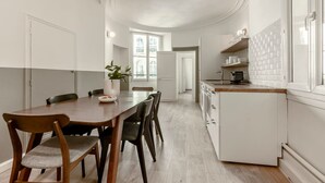 Uma cozinha moderna com armários brancos, bancada de madeira e forno embutido.