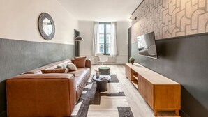 Un salon moderne avec un canapé en cuir, une table basse et un téléviseur fixé au mur.