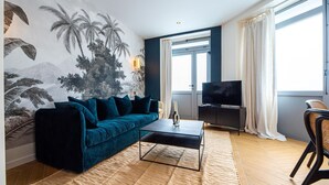 En moderne stue med en mørkeblå sofa, et sofabord og et fladskærms-tv på et mørkt træskab.