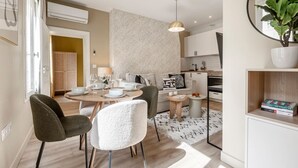 A modern kitchen with white cabinets, a round dining table, and a hanging pendant light.