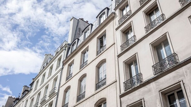 A row of classical European-style buildings with uniform balconies and arched windows.
