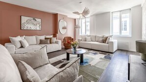Un salon moderne avec deux canapés blancs, une table basse ronde et un grand miroir.