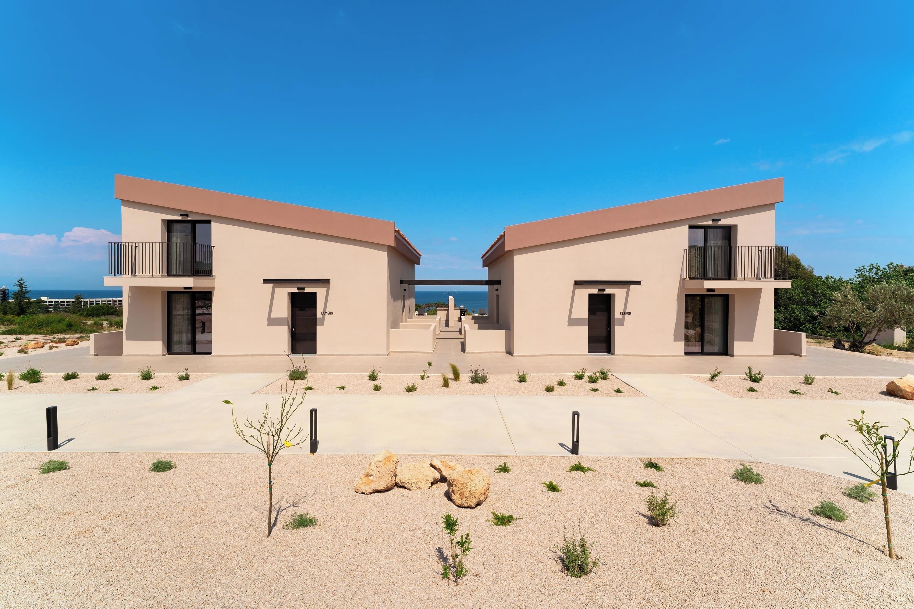 Un edificio simmetrico con un ingresso centrale, balconi e vista sul mare.