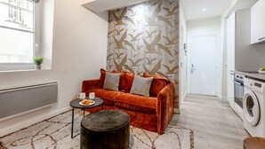A compact living space with a sofa, a small round table, and a washing machine.