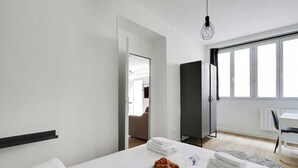 A modern hotel room with a bed, breakfast setup, and a view of the outside.