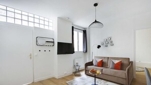 A modern living room with a sofa, a coffee table, and a TV mounted on the wall.