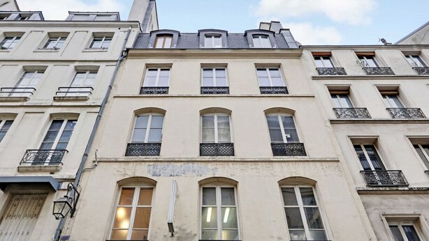 A multi-story building with a classic architectural style, featuring arched windows and balconies with wrought iron railings.