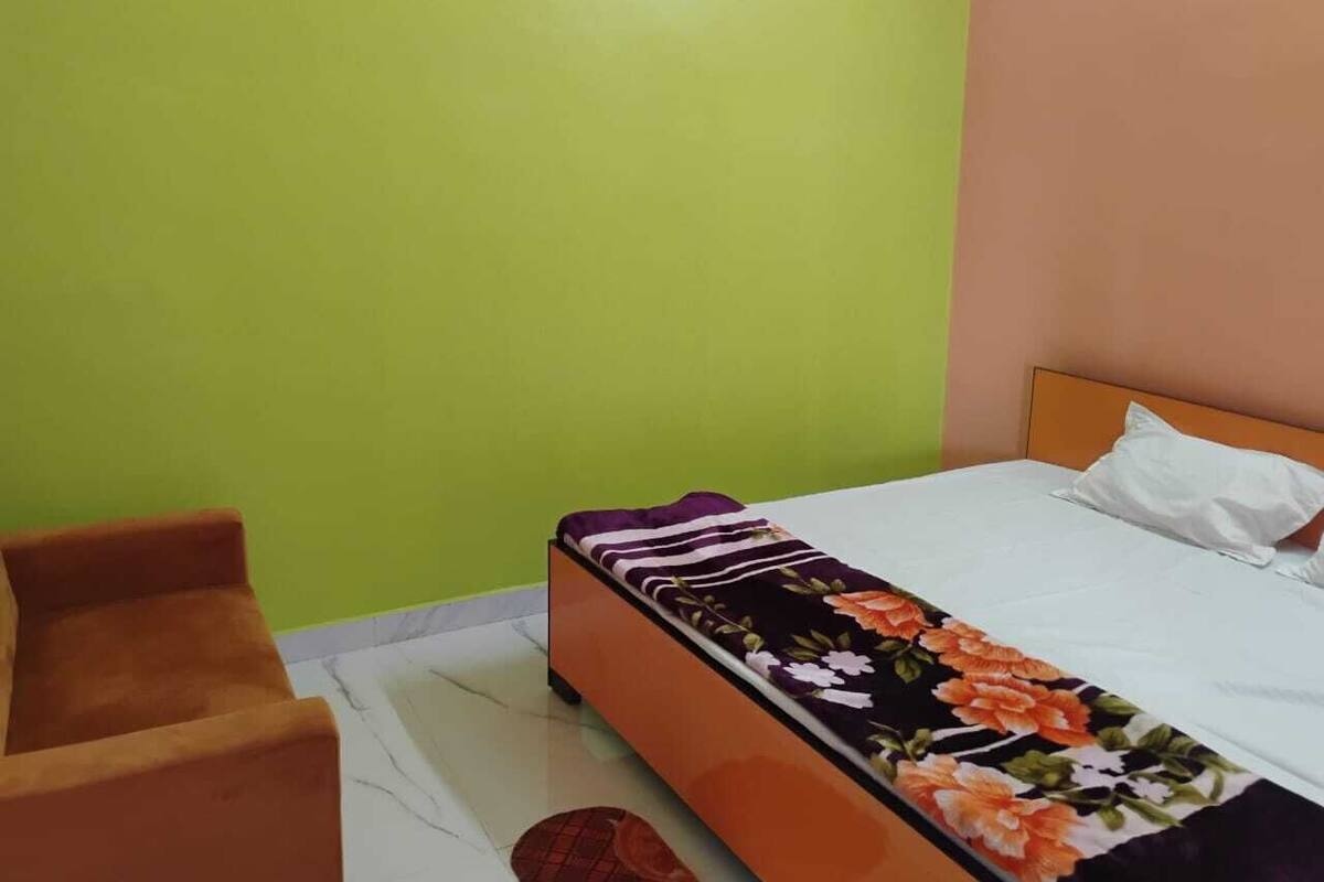 A bedroom with a bed, a wooden chair, and a green and peach wall.