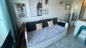 Ein modernes Wohnzimmer mit einer Couch, Kunstwerken an der Wand und einer Küchenzeile.