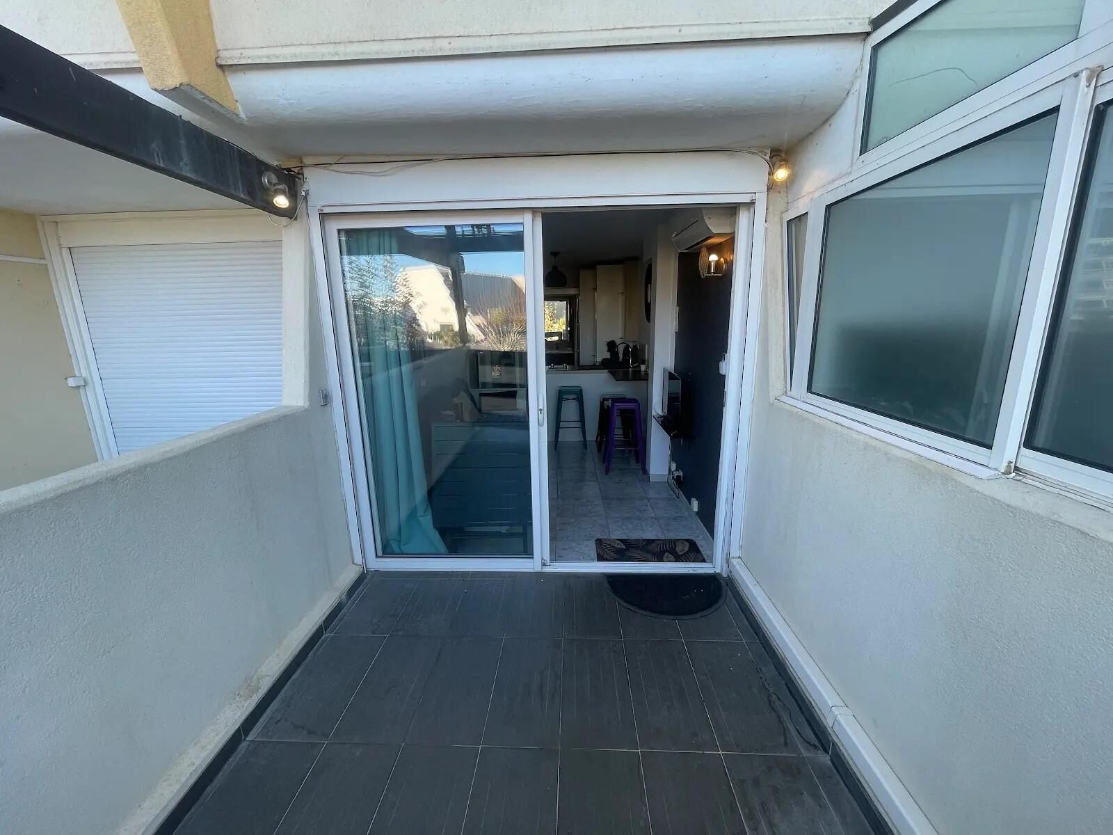 A narrow outdoor corridor with a sliding glass door leading to a patio area.