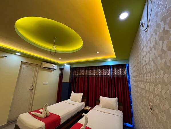 A hotel room with two beds, a ceiling light, and a patterned wall.