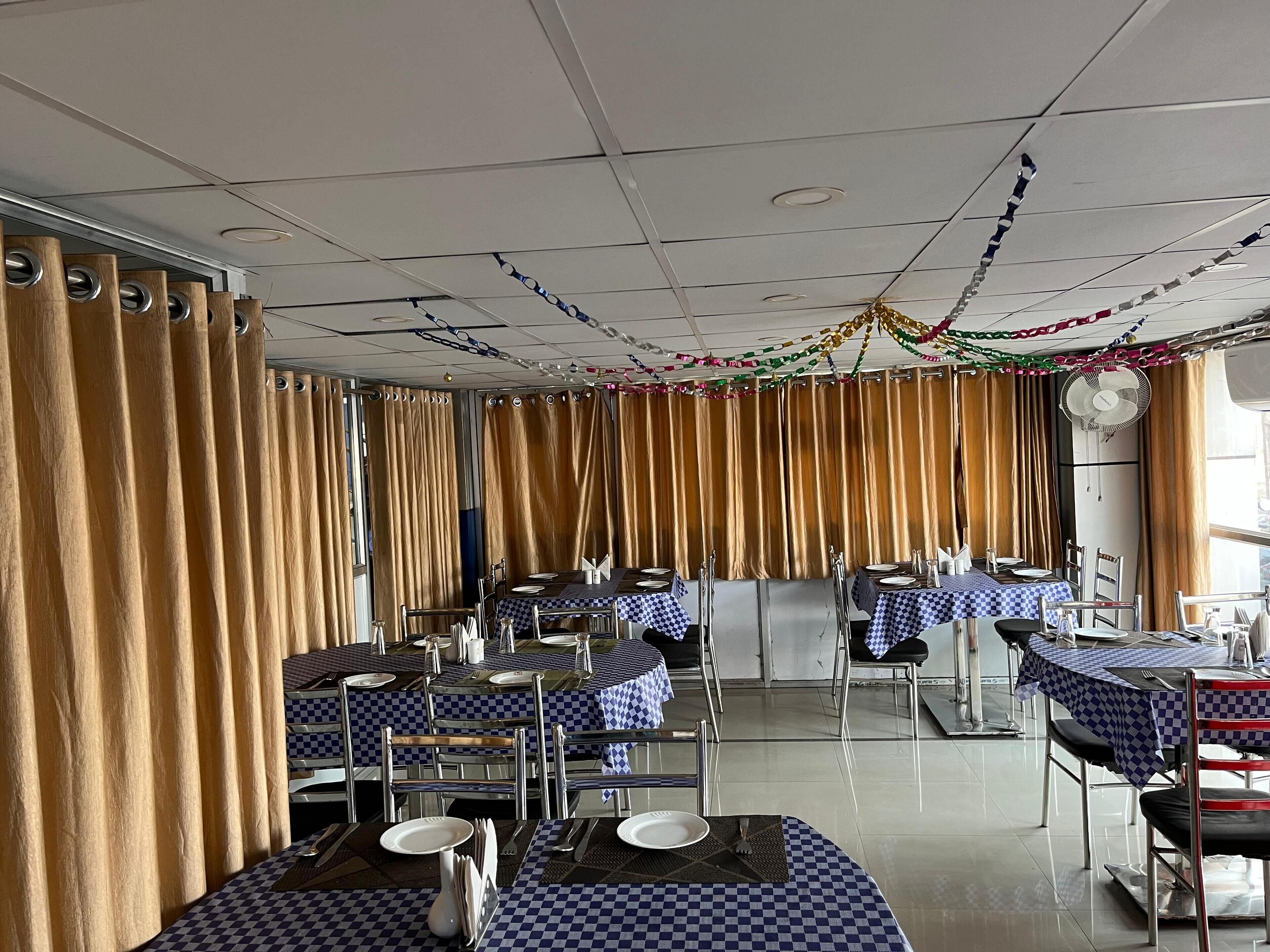 Un restaurant avec des nappes à carreaux, des chaises en métal et des rideaux.