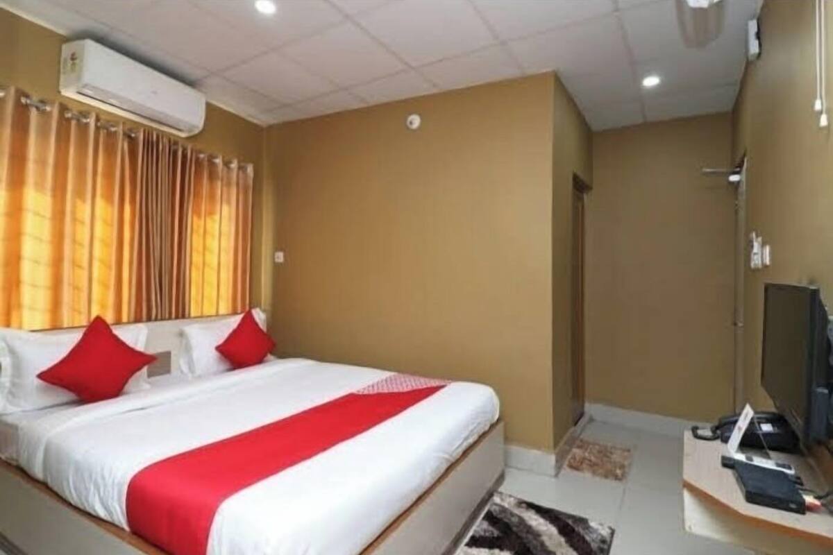 Ett hotellrum med en säng, ett skrivbord, luftkonditionering och en dusch.
