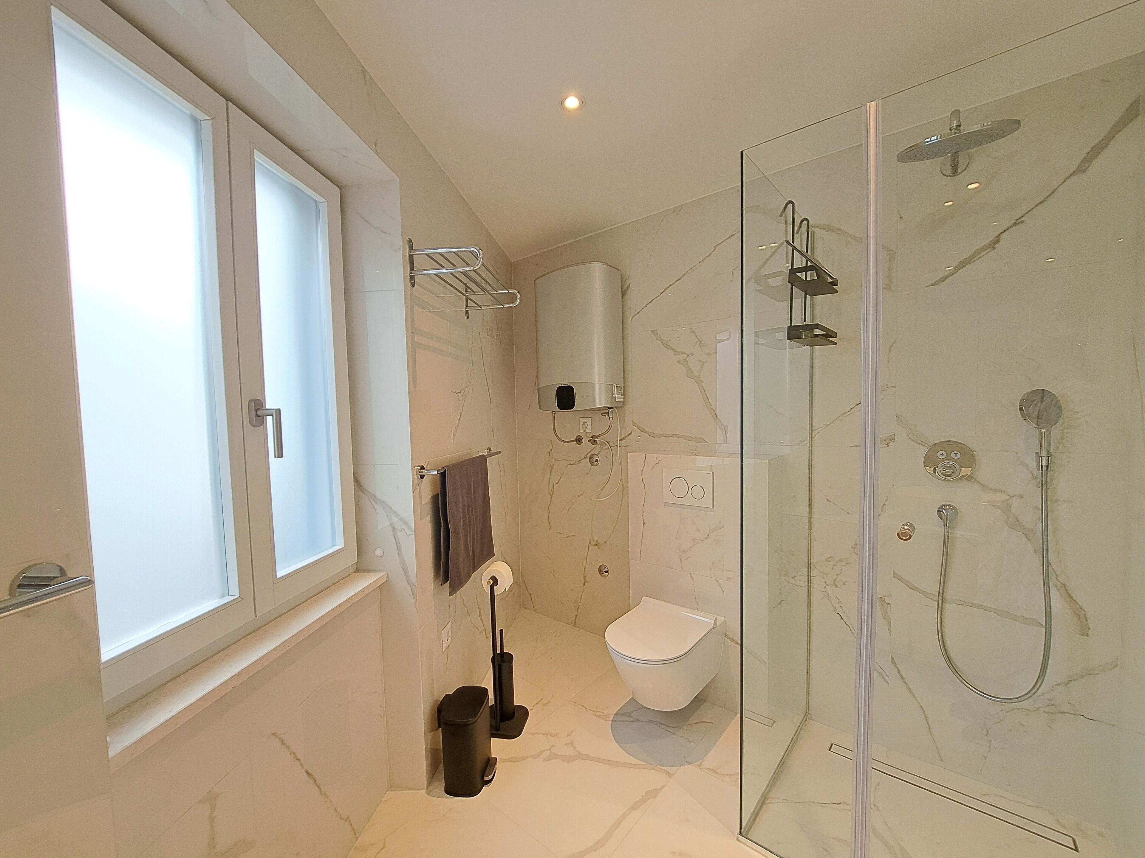 A modern bathroom with a glass-enclosed shower, a toilet, and a bidet.
