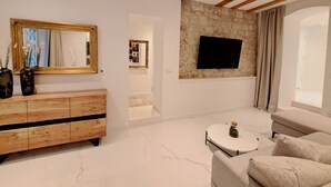 Un soggiorno moderno con soffitto in legno, una parete d'accento in pietra, un televisore a schermo piatto, un divano e un mobile in legno.