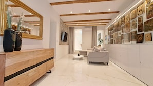 Un soggiorno moderno con una panca di legno, un divano bianco e una parete decorata con quadri.