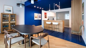 A modern dining area with a dark wooden table and chairs, a bar area with stools, and a blue accent wall.