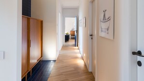 A hallway with wooden flooring, a wardrobe, and a door with a framed picture.