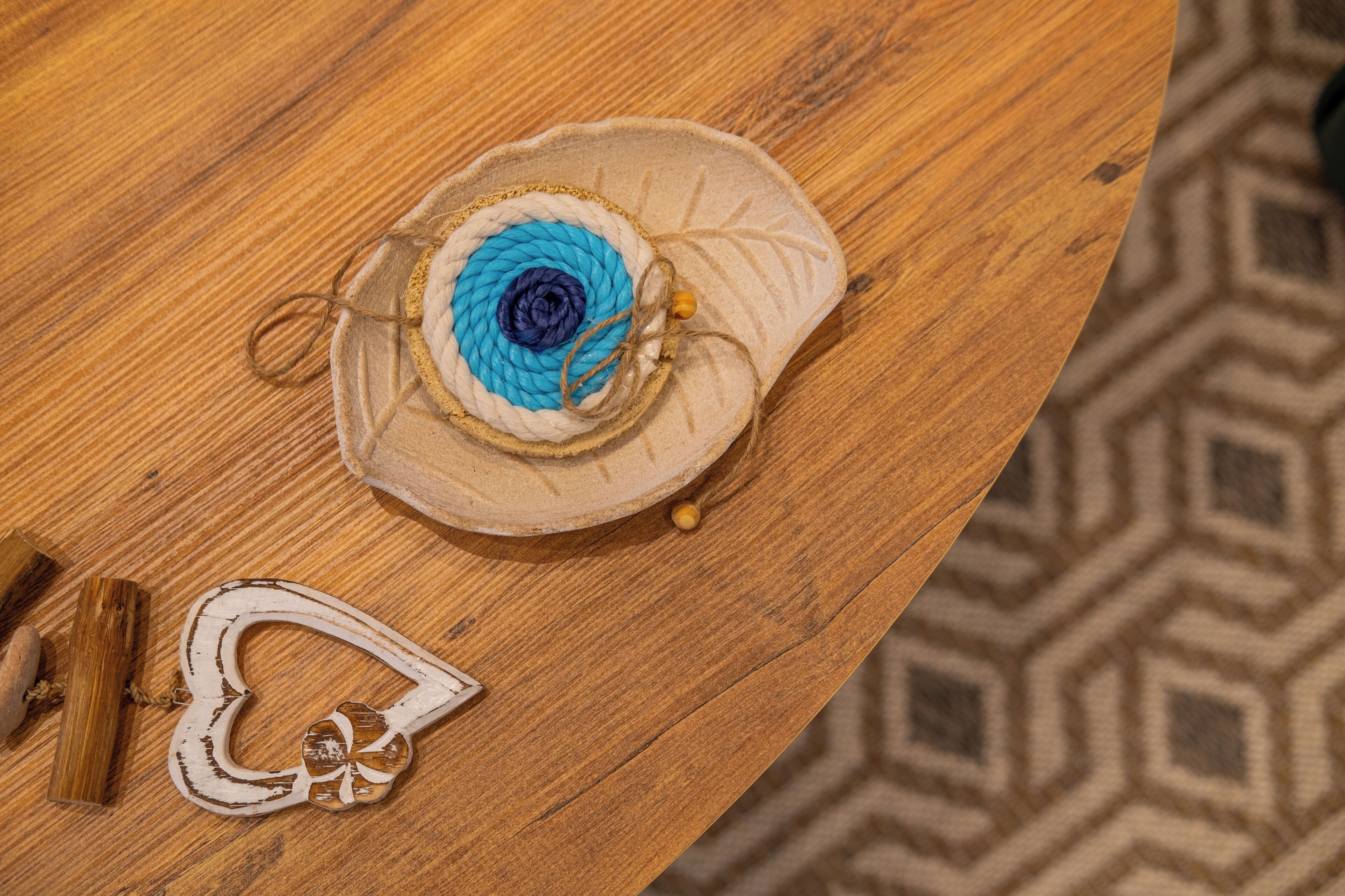 Een houten tafel met een decoratie en een klein, wit, hartvormig object.