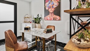 A modern dining area with a marble table, leather chairs, and a large floral painting on the wall. - Lazuli Hermes Apartments (Larnaca)