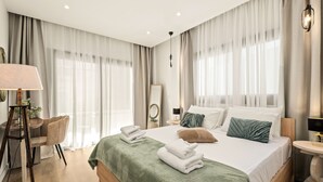 A modern hotel room with a large bed, a desk, a chair, and a mirror. - Lazuli Hermes Apartments (Larnaca)