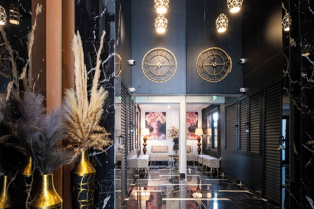 A luxurious lobby with a black and white marble floor, gold accents, and modern lighting fixtures.