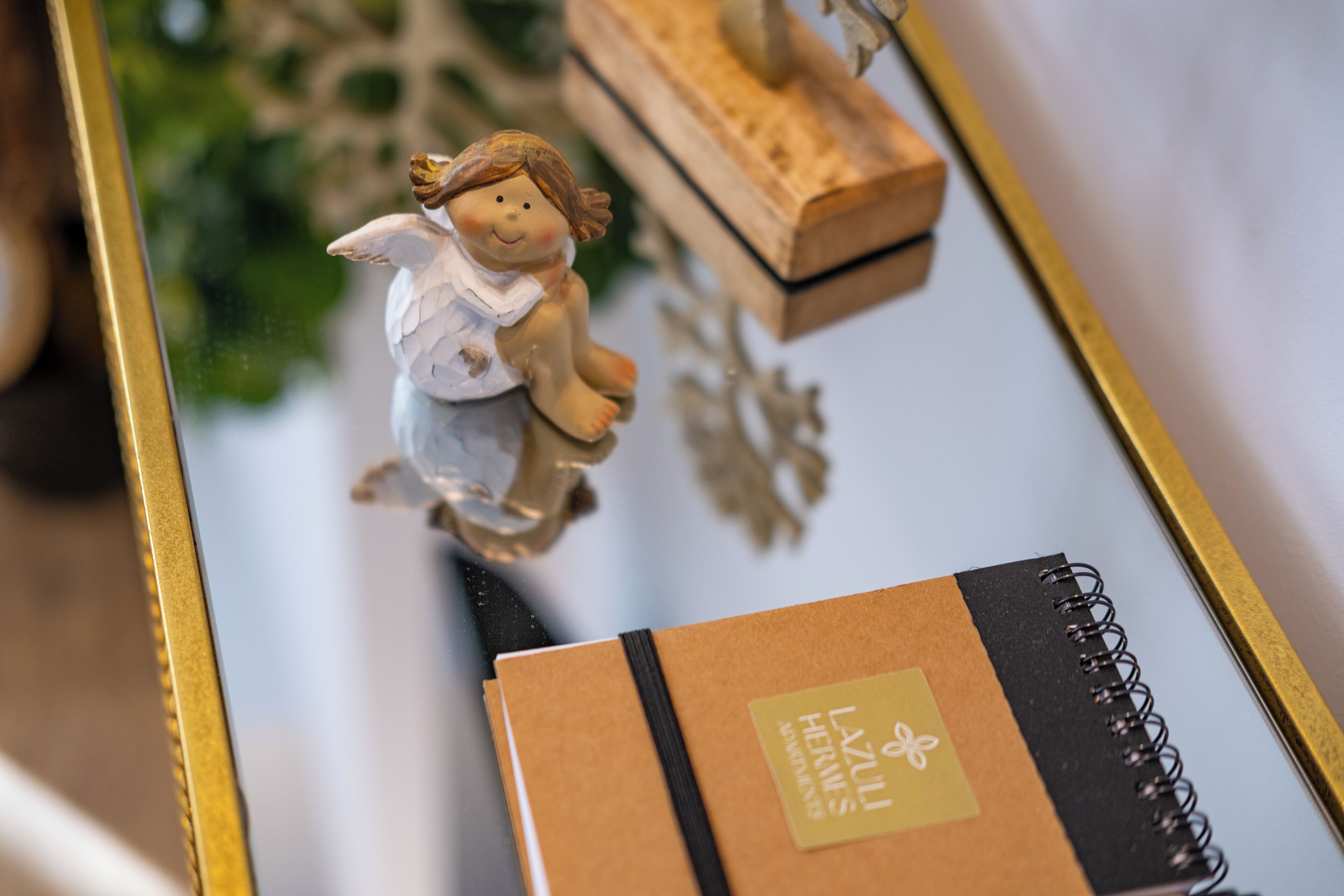 Un cuaderno con una etiqueta, una caja de madera y una figurita sobre una superficie reflectante.