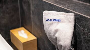 A bathroom with a towel rack holding a white towel with "LAZULI HERMES" embroidered in blue.
