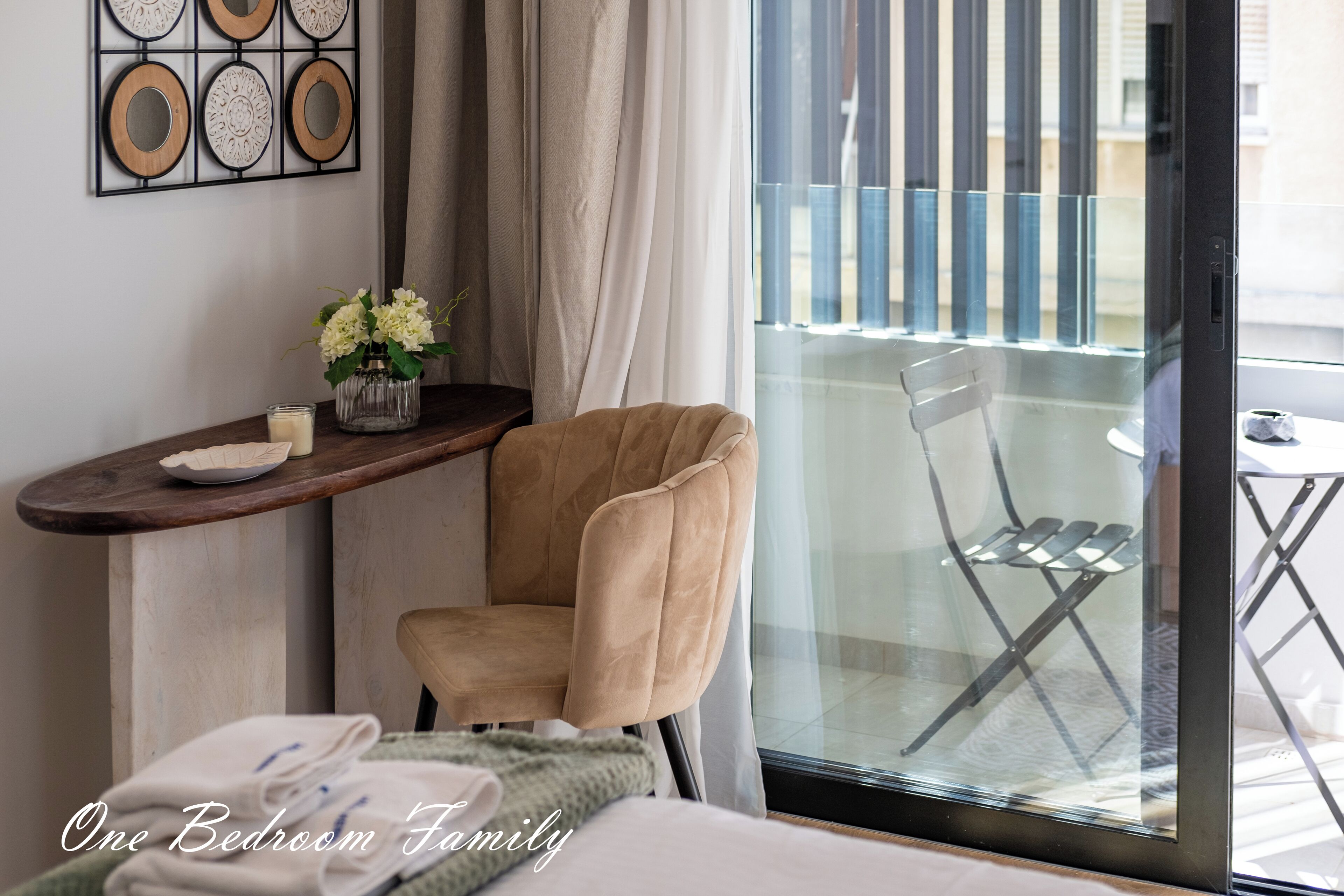 Une chambre à coucher comprenant un lit, une chaise, une petite table avec un vase de fleurs et une fenêtre donnant sur un balcon.