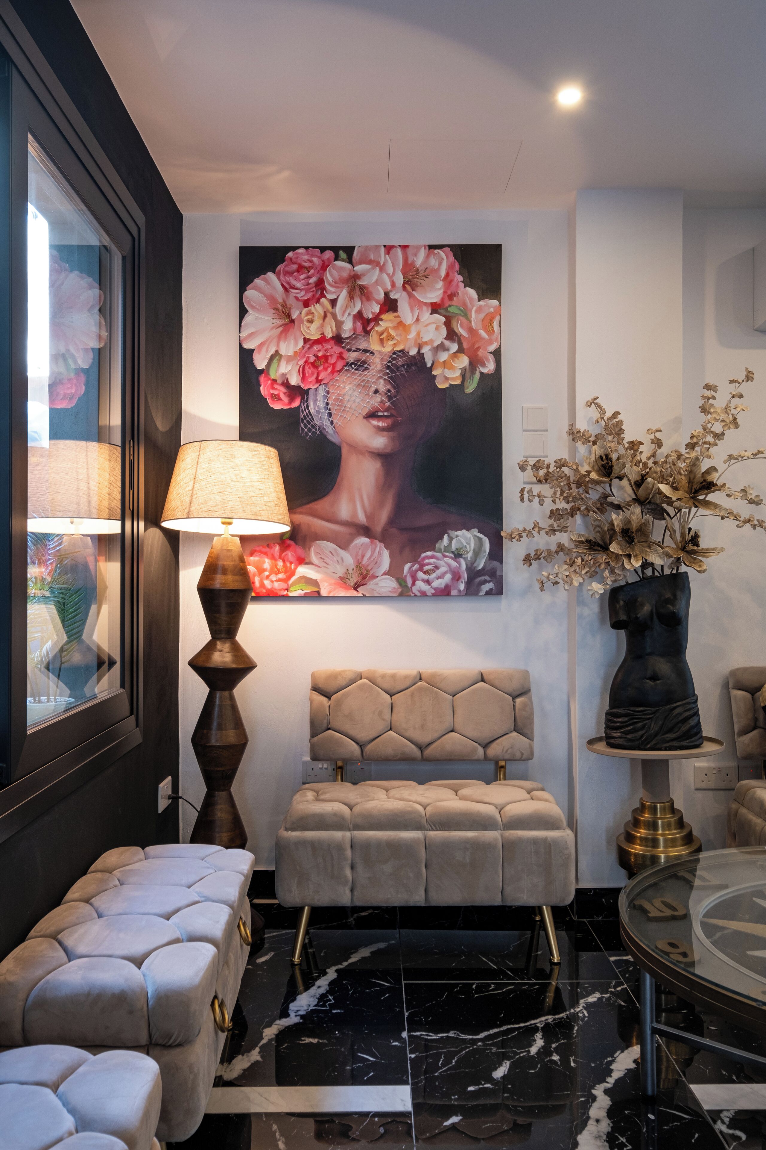 Una sala moderna con un cuadro floral grande, una mesa de centro redonda y un banco tapizado en color beige.