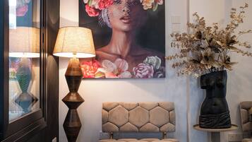 Una sala moderna con un cuadro floral grande, una mesa de centro redonda y un banco tapizado en color beige.