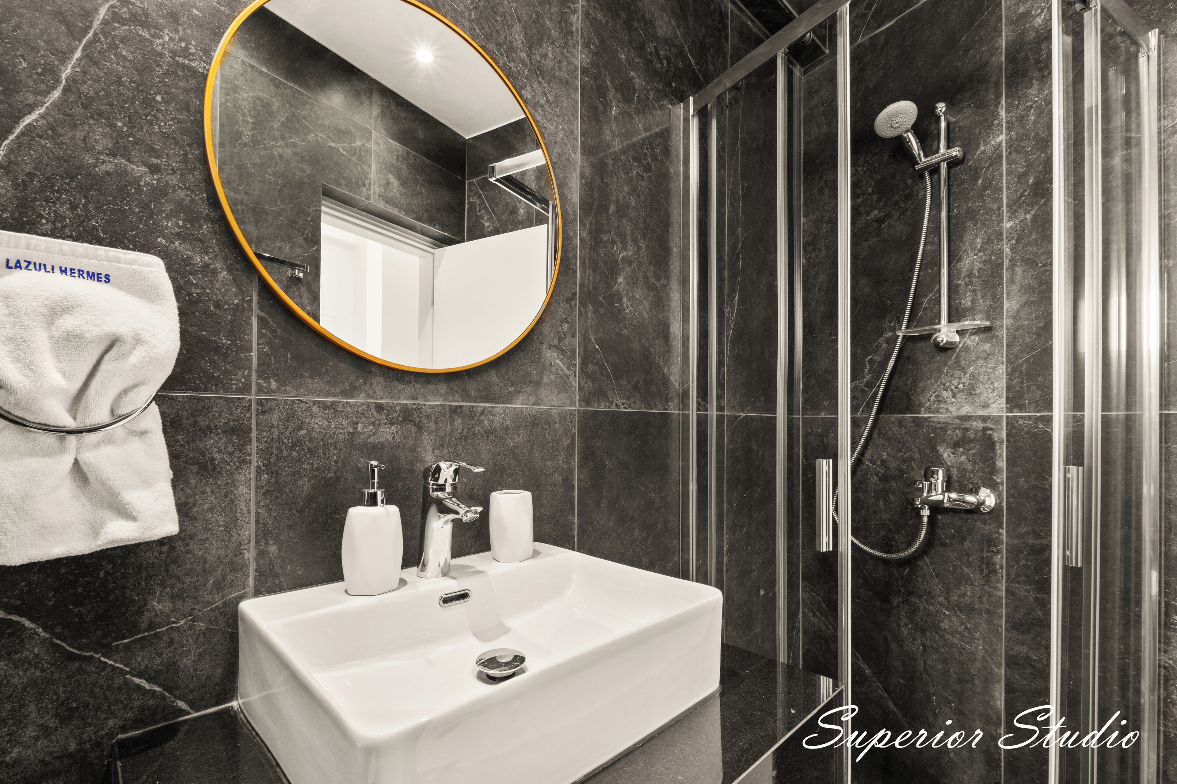 A modern bathroom with a white sink, a round mirror, and a glass-enclosed shower.